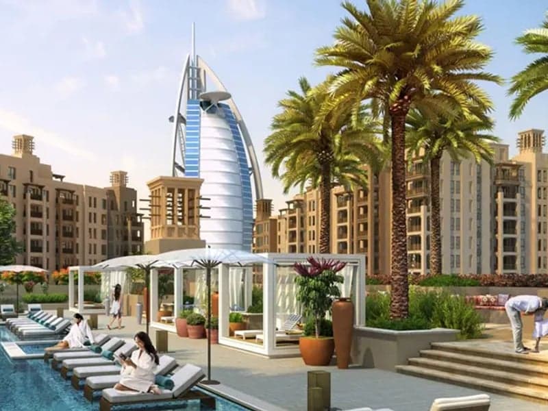 A stunning daytime view of the Madinat Jumeirah Living community, with its signature architecture and the Burj Al Arab in the background, representing a dream home purchase.